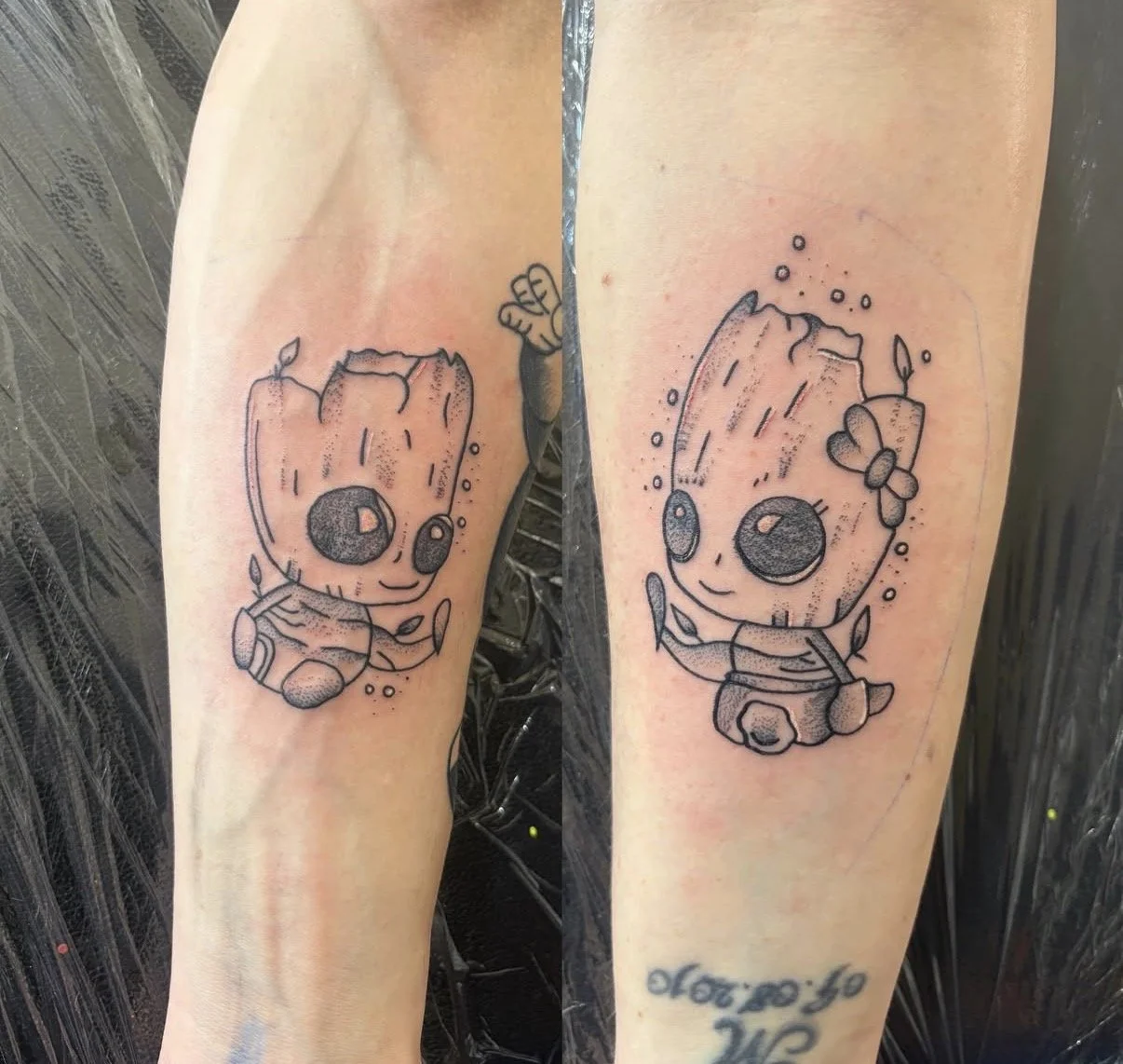 Tattoo eines cartoonartigen Baums mit großem Kopf, großen Augen, kleinen Armen und Beinen, mit Blättern und Bienen. Runde Details im Stil eines Kinderbuchs.