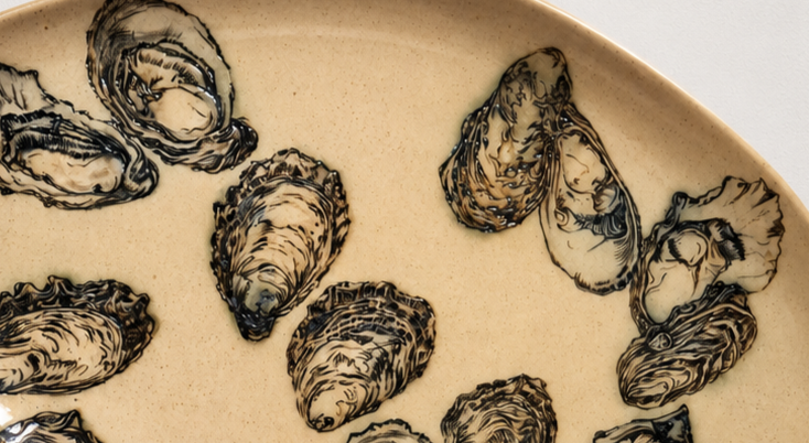 Close-up of several opened oyster shells on a beige plate.