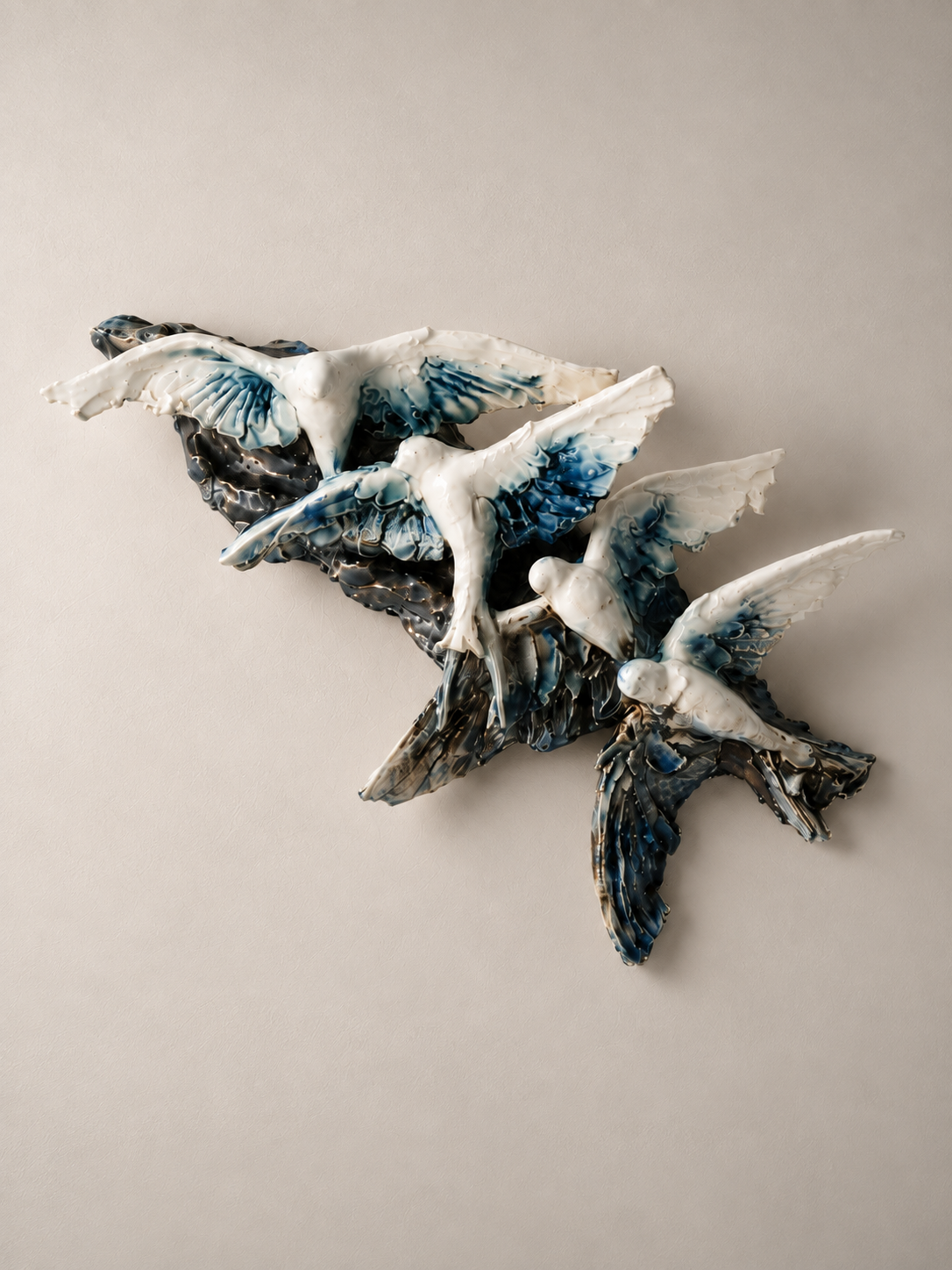 Ceramic sculpture of flying birds painted with blue, white, and black glaze on a plain background.