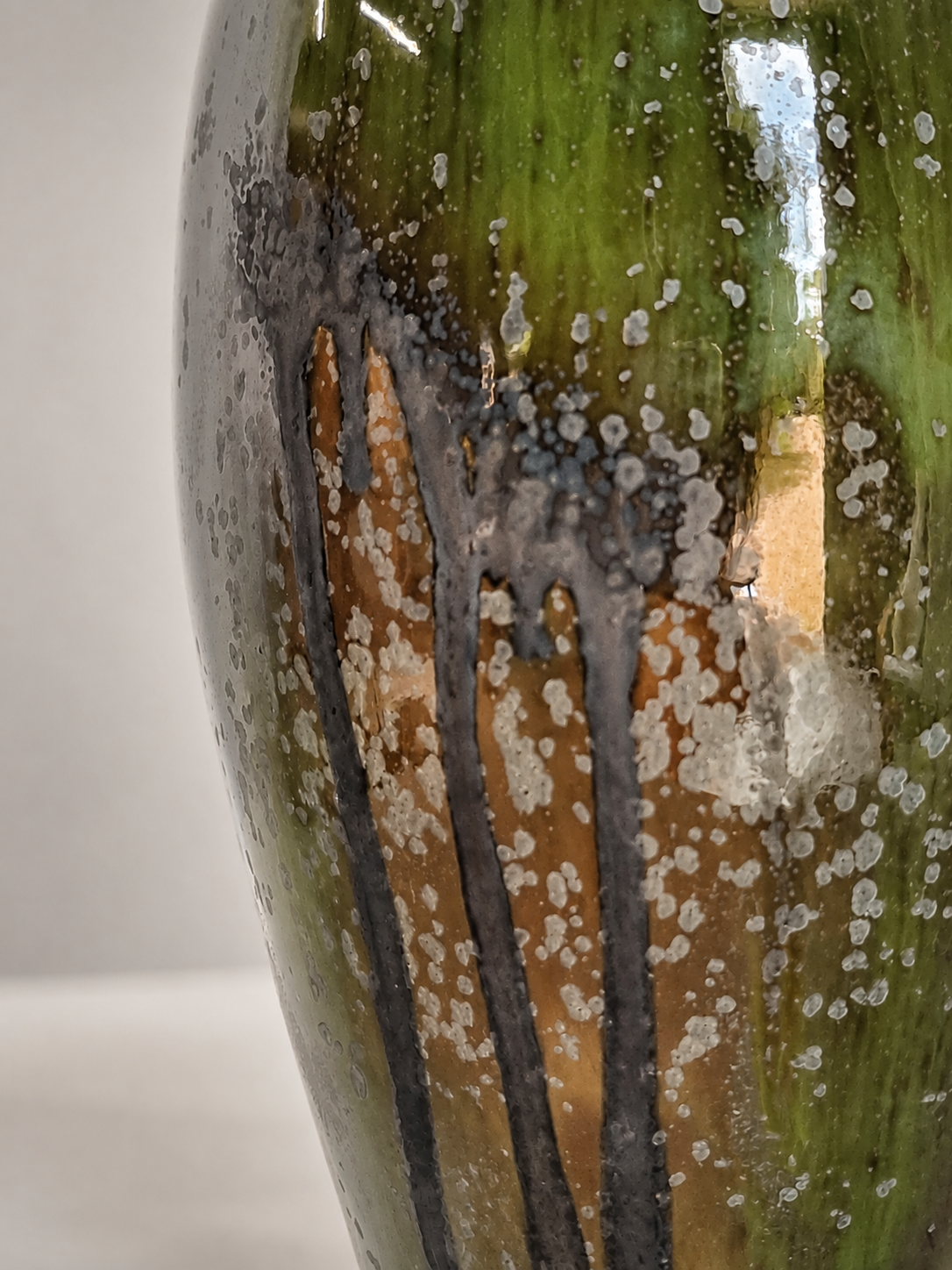 A close-up of a green vessel with some black and brown lines, covered in water droplets and some foam or bubbles.