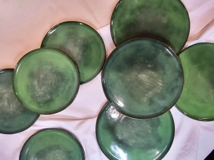 Several green round glass bowls or dishes on a light-colored fabric surface.
