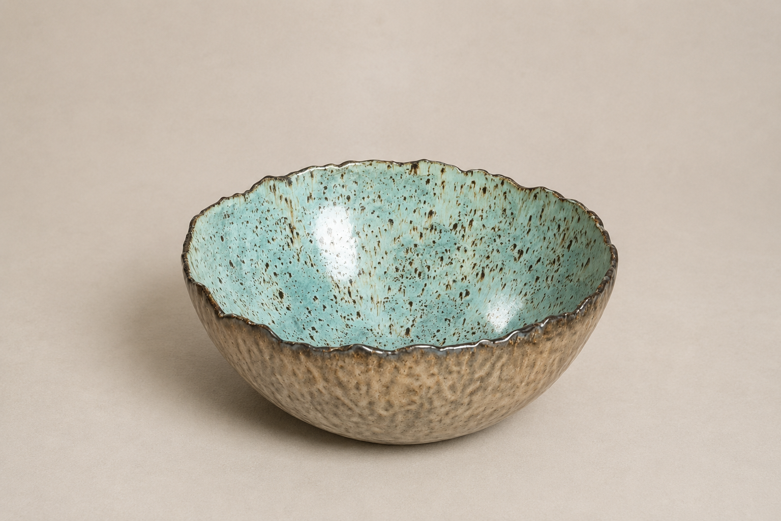 A ceramic bowl with a textured, speckled outer surface and a smooth, turquoise interior with speckled pattern.