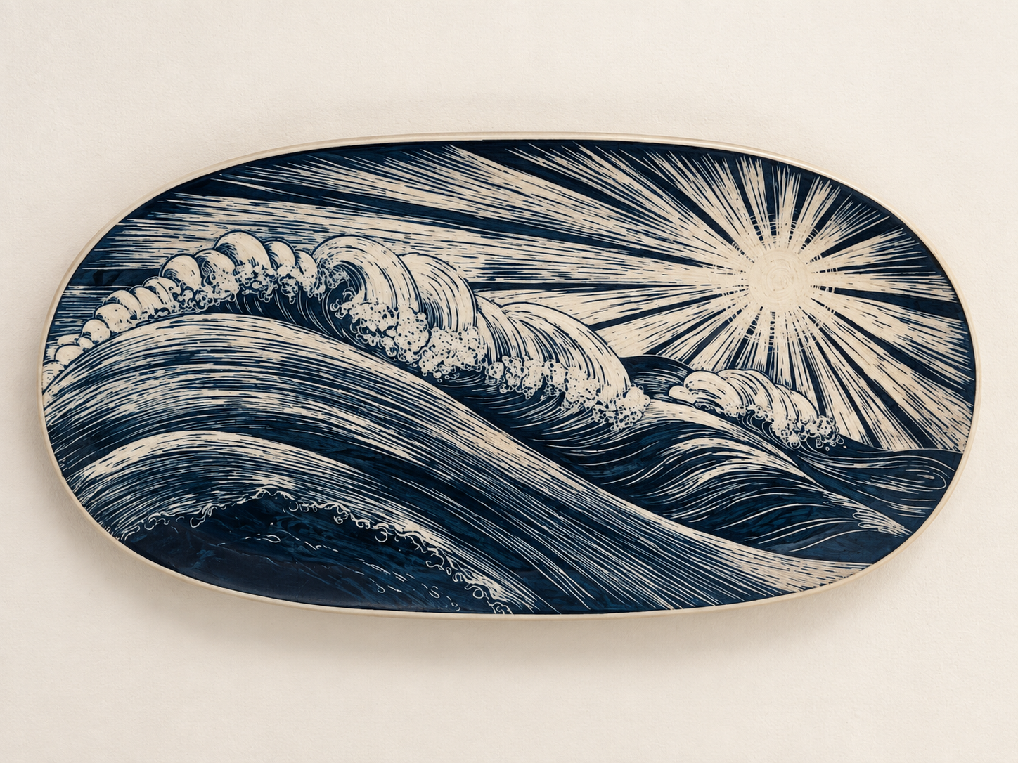 Oval plate with a blue and white artistic depiction of ocean waves and a bright sun with radiating rays.
