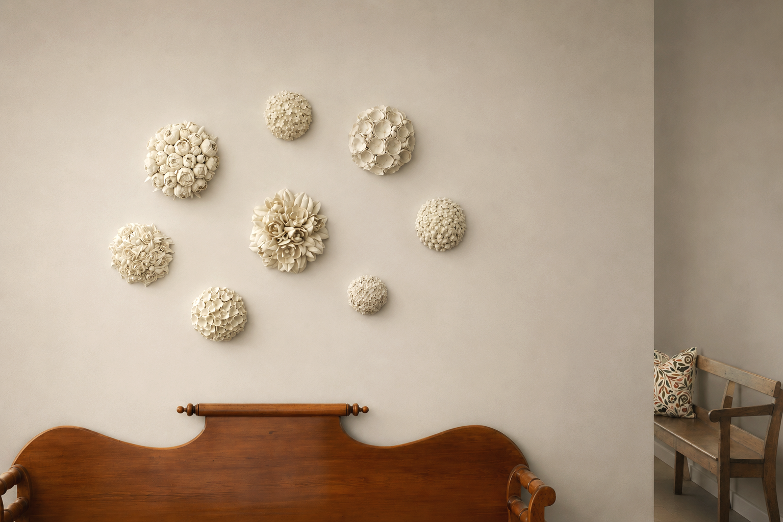 Decorative white floral wall art above a wooden bed with a simple headboard, partially visible in a softly lit room with a corner and a wooden bench with a cushion.