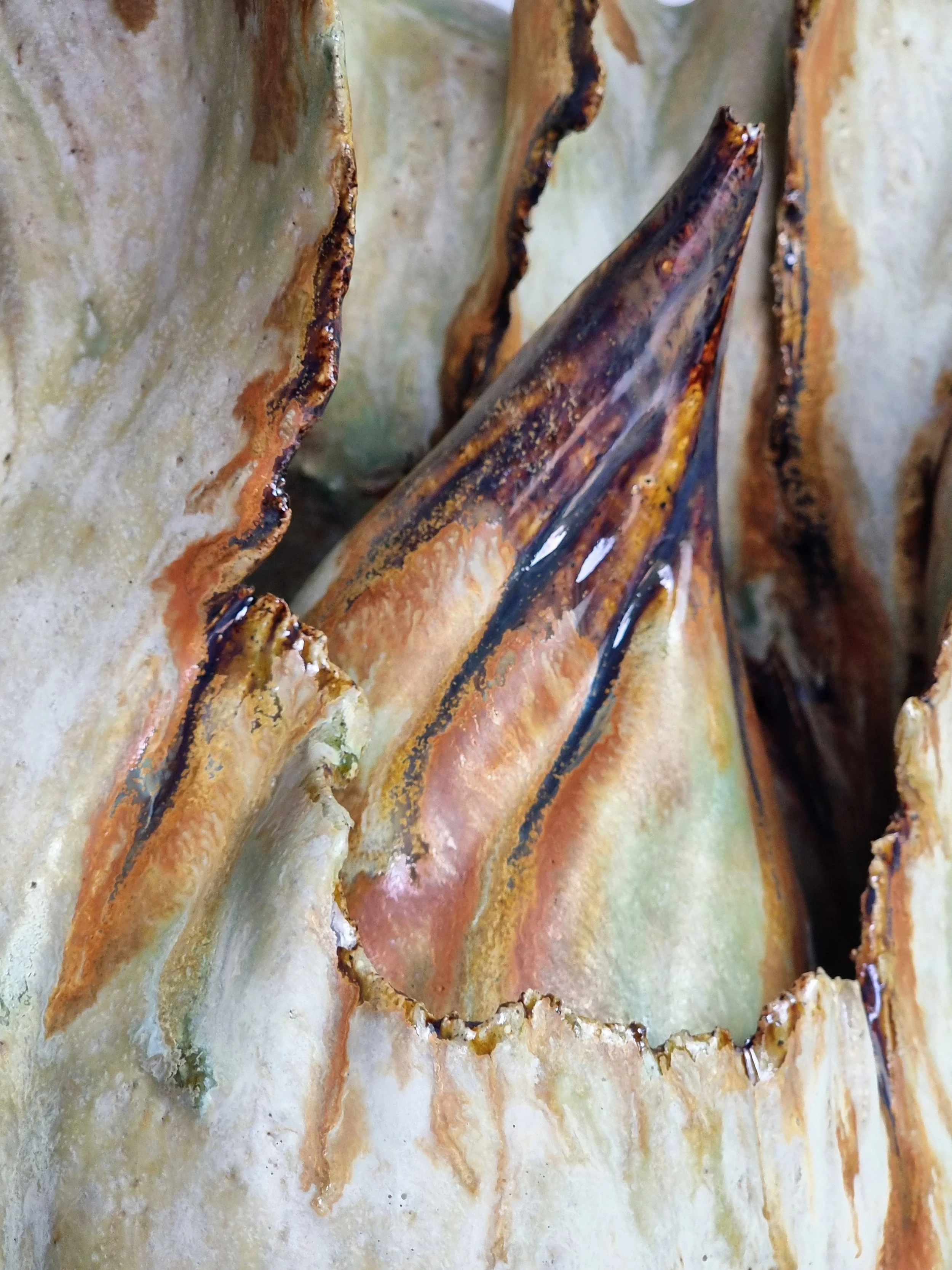 Close-up of a decorative vessel with curved ceramic in earthy glossy tones.