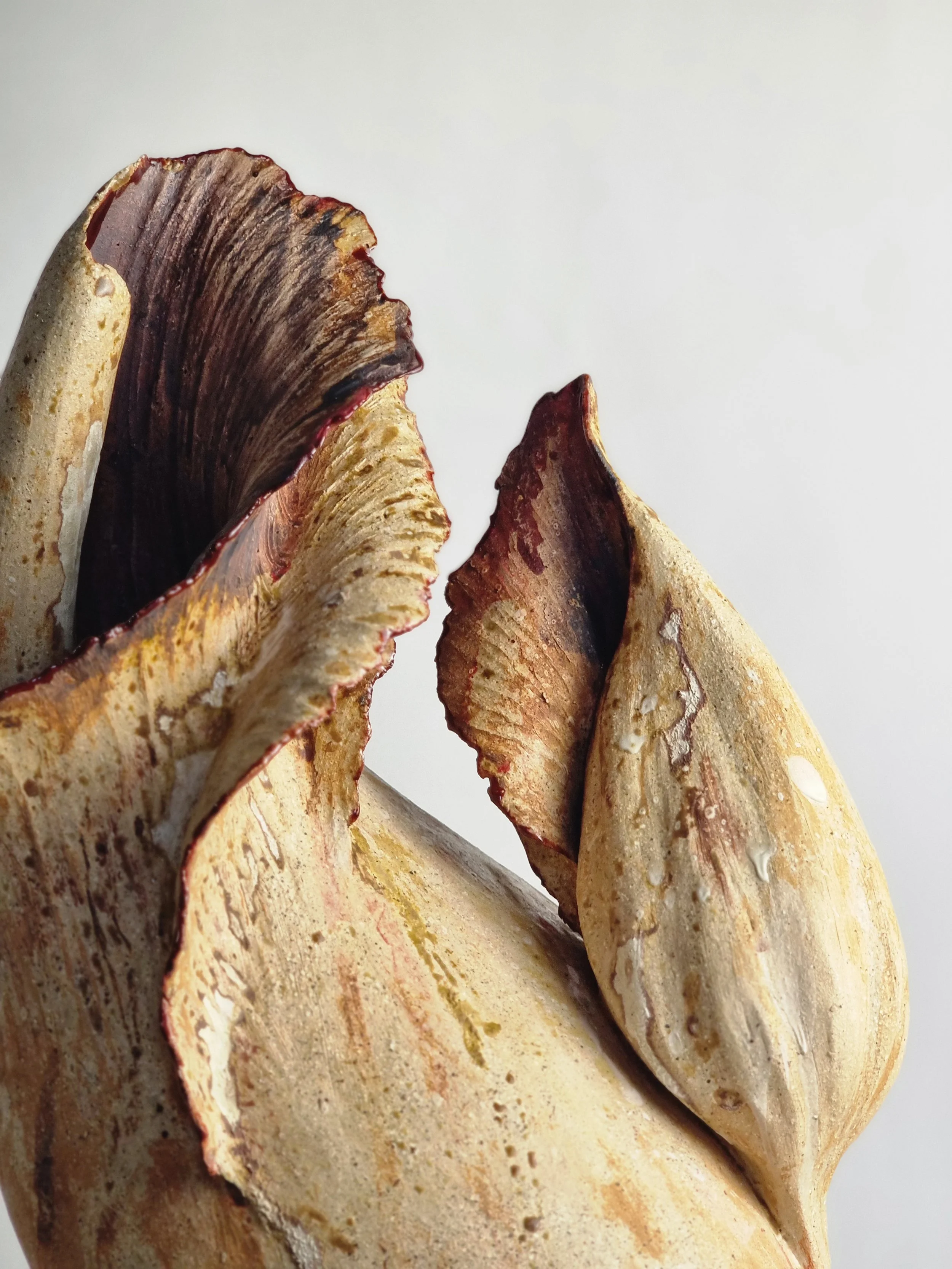 Close-up of a textured vessel  with brown, beige, and cream colors against a plain white background.