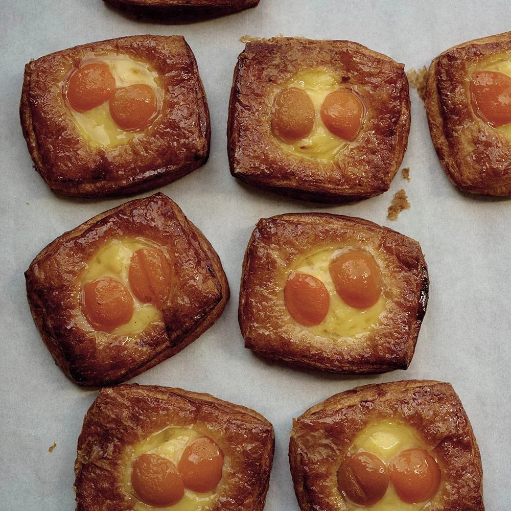 Six breakfast pastries with two egg yolks each on a baking sheet.