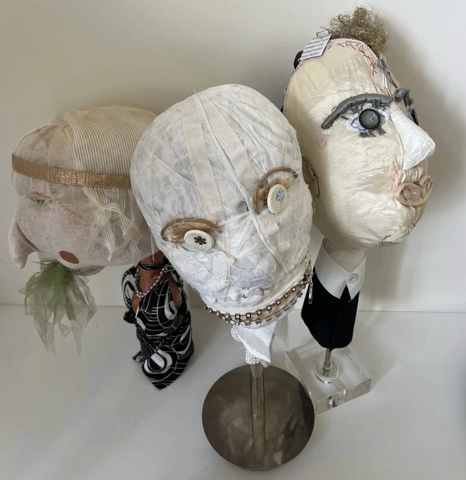 Collection of three artistic mannequins made of paper or fabric with various accessories and features, displayed together against a plain white background.