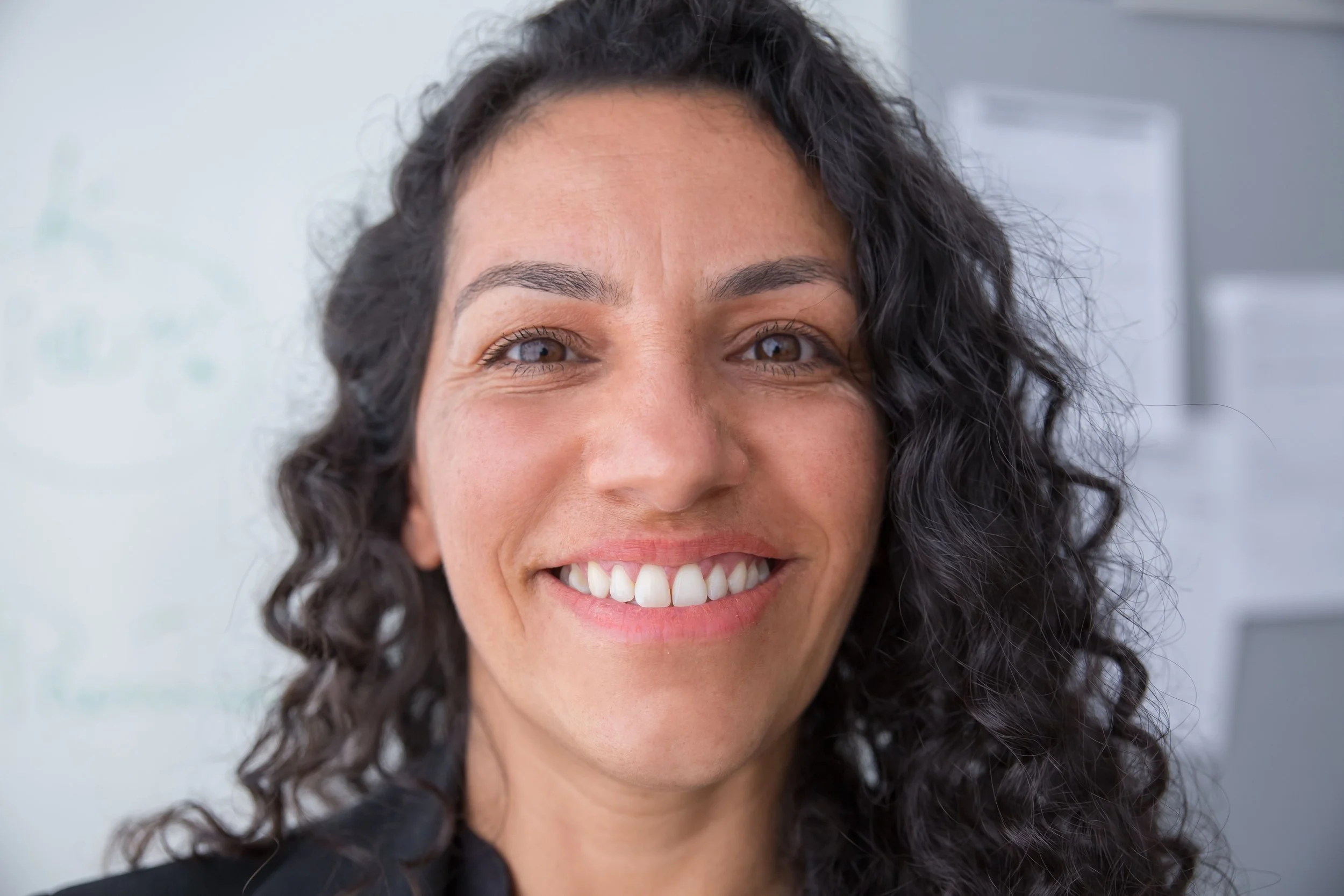 Headshot of smiling female tutor with long braids wearing a lanyard.