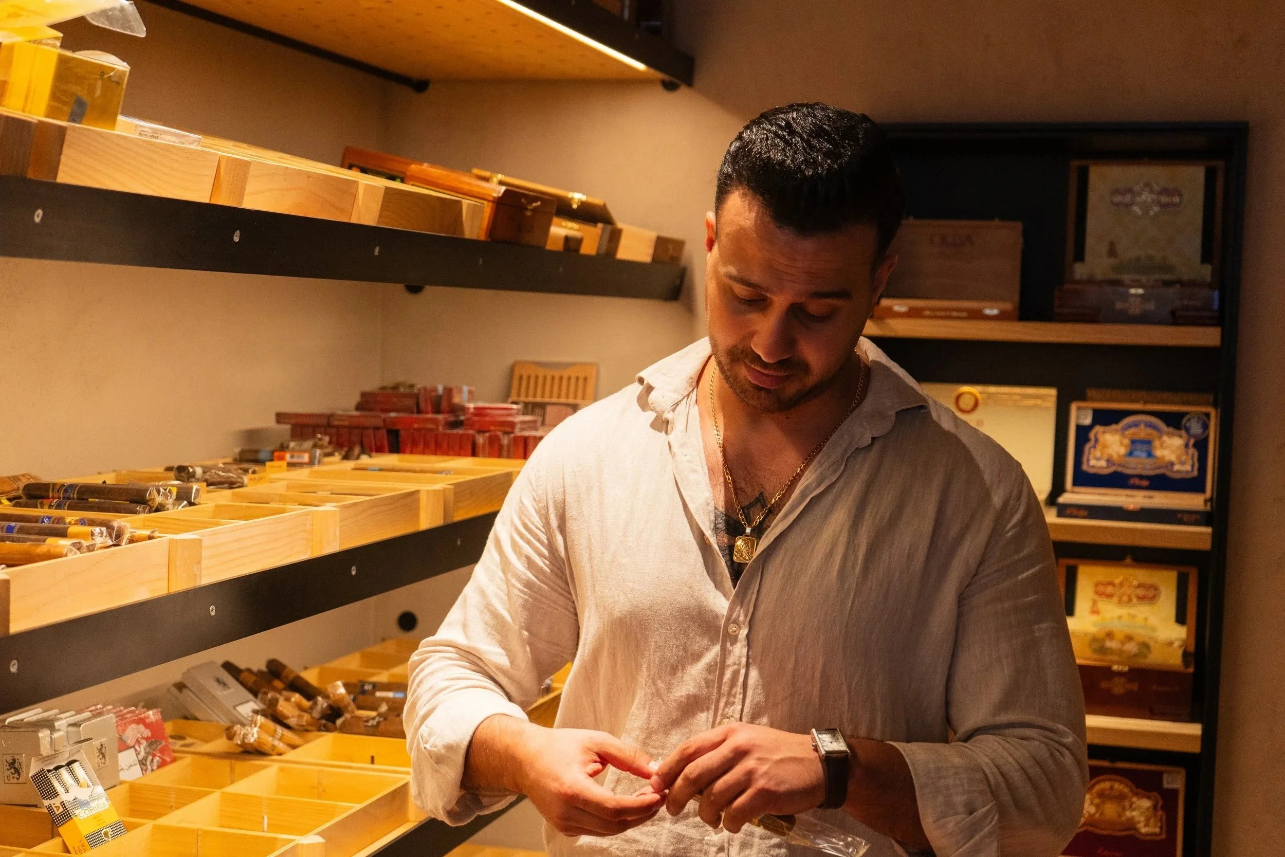   Yousef Mazahrah  in the cigar showroom at  Fyxx , taking a cigar from its plastic-wrapped package.  31 August 2026 © Photo by Yasr Abdalla  