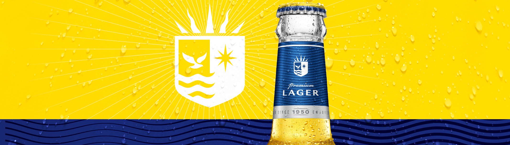 A bottle of Carib lager beer with a blue label, set against a background with yellow and blue colours and water droplets.