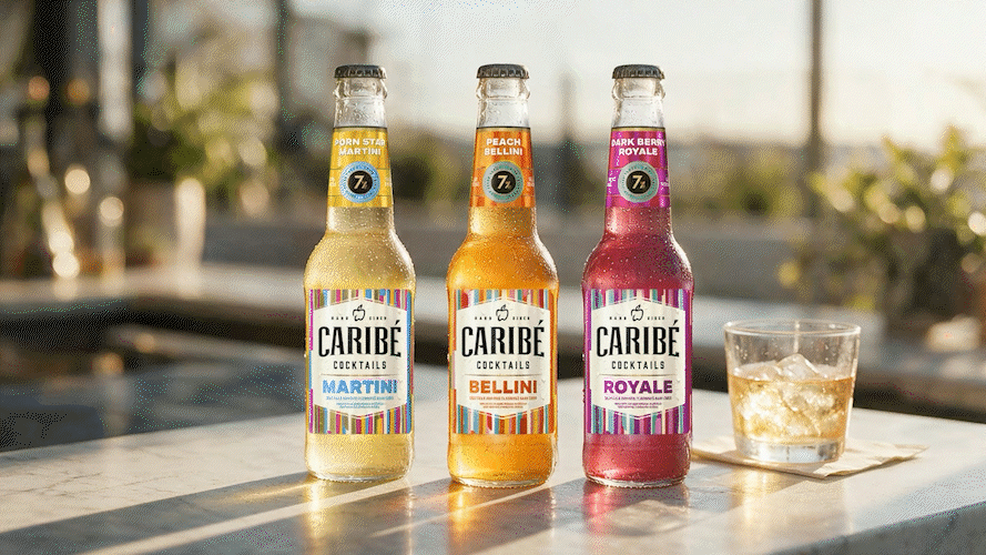 Three bottles of Caribé hard cider cocktails with colorful labels, each with a different flavor: Martini, Bellini, and Royale, placed on a bar counter with a glass of ice and drink beside them in an outdoor setting.
