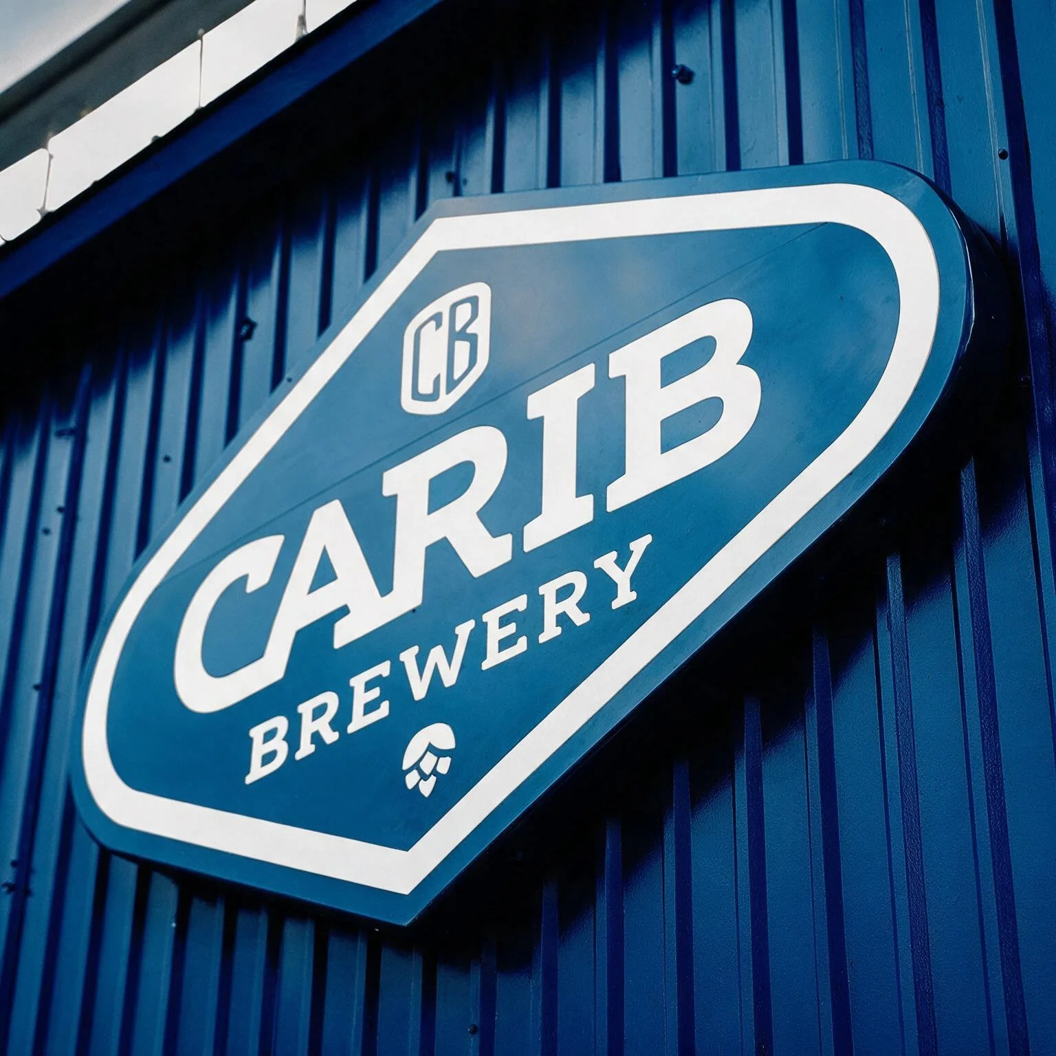 Close-up of a blue sign reading 'CARRY Brewing' mounted on a dark blue wooden wall.