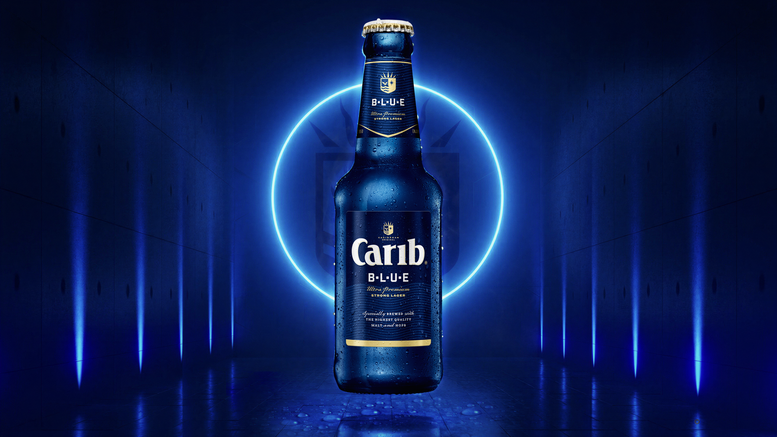 A blue bottle of Carib Blue beer with condensation droplets, illuminated by a blue neon circle and lines in a dark setting.
