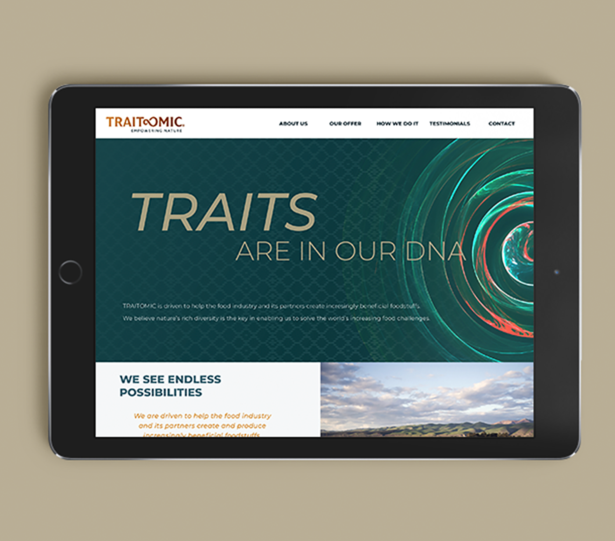 A tablet displaying a website for Traitomic, a company involved in natural trait engineering, with navigation options such as About Us, Our Offer, How We Help It, Testimonials, and Contact. The website features a graphic design with colorful, swirling lines and a background of resembling a digital or genetic pattern.