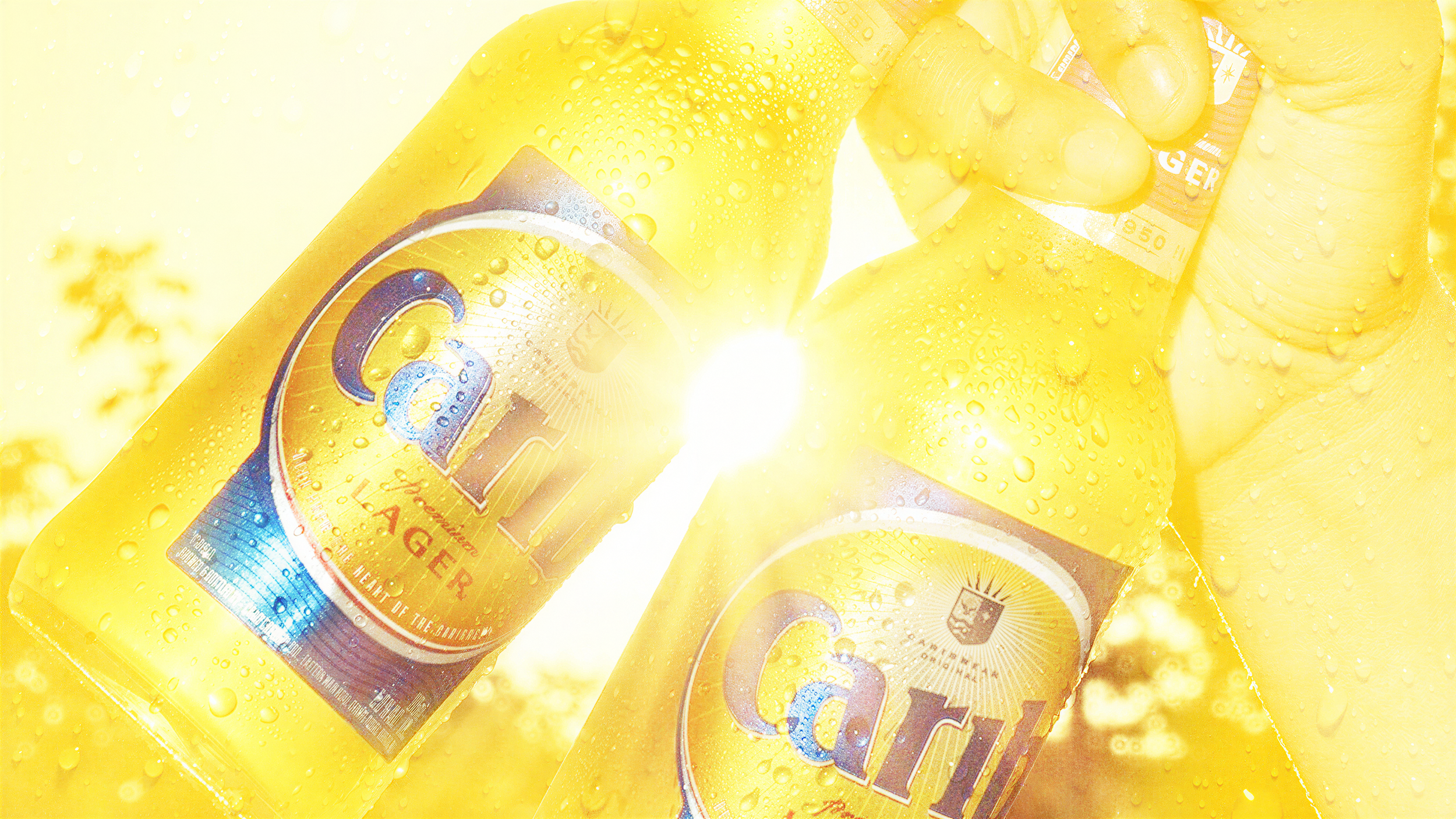 Multiple bottles of Carib Beer with condensation and water droplets, backlit with sunlight.