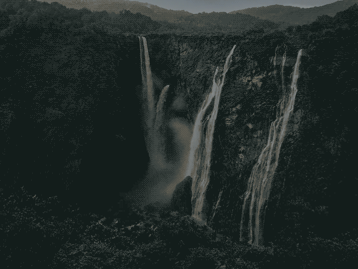 A large waterfall cascading down a rugged, dark cliffside surrounded by lush greenery.