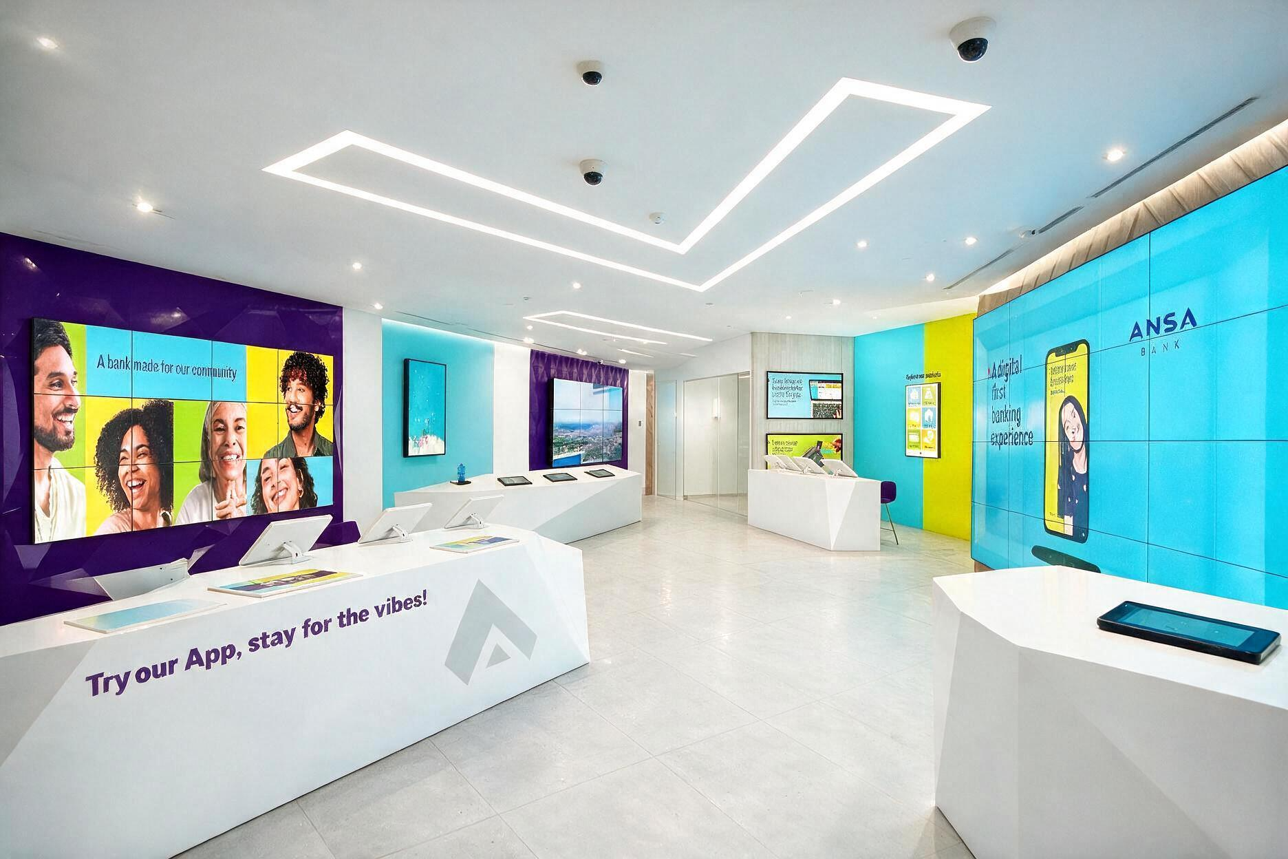Modern bank interior with colorful digital displays, tablets on white counters, and seating area, promoting a digital banking app.