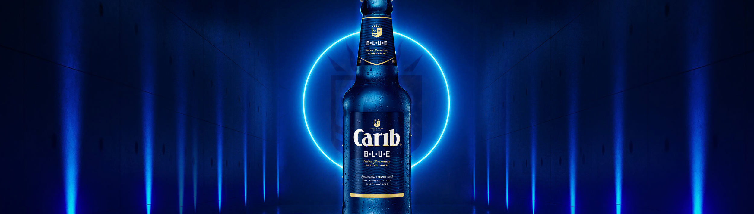 A Bottle of Carib Blue beer illuminated with blue neon lights in a dark tunnel-like setting.