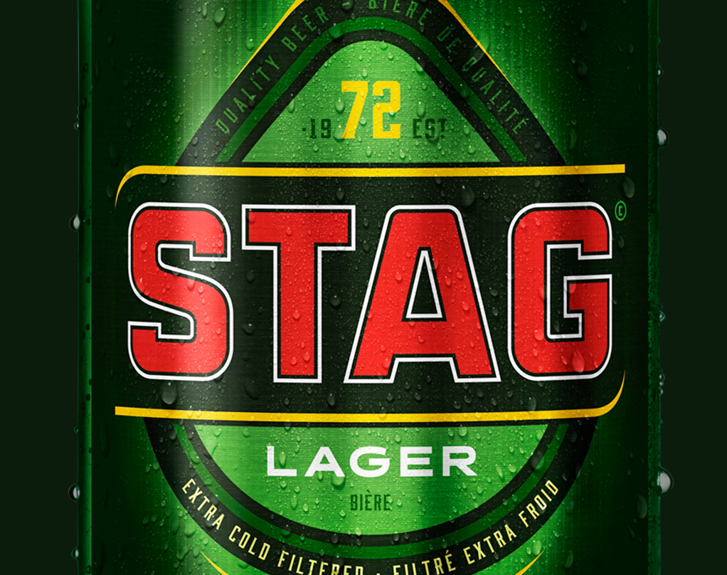 Close-up of a green Stag Lager beer can with water droplets, featuring bold red and white text and a green and black plectrum shaped logo.