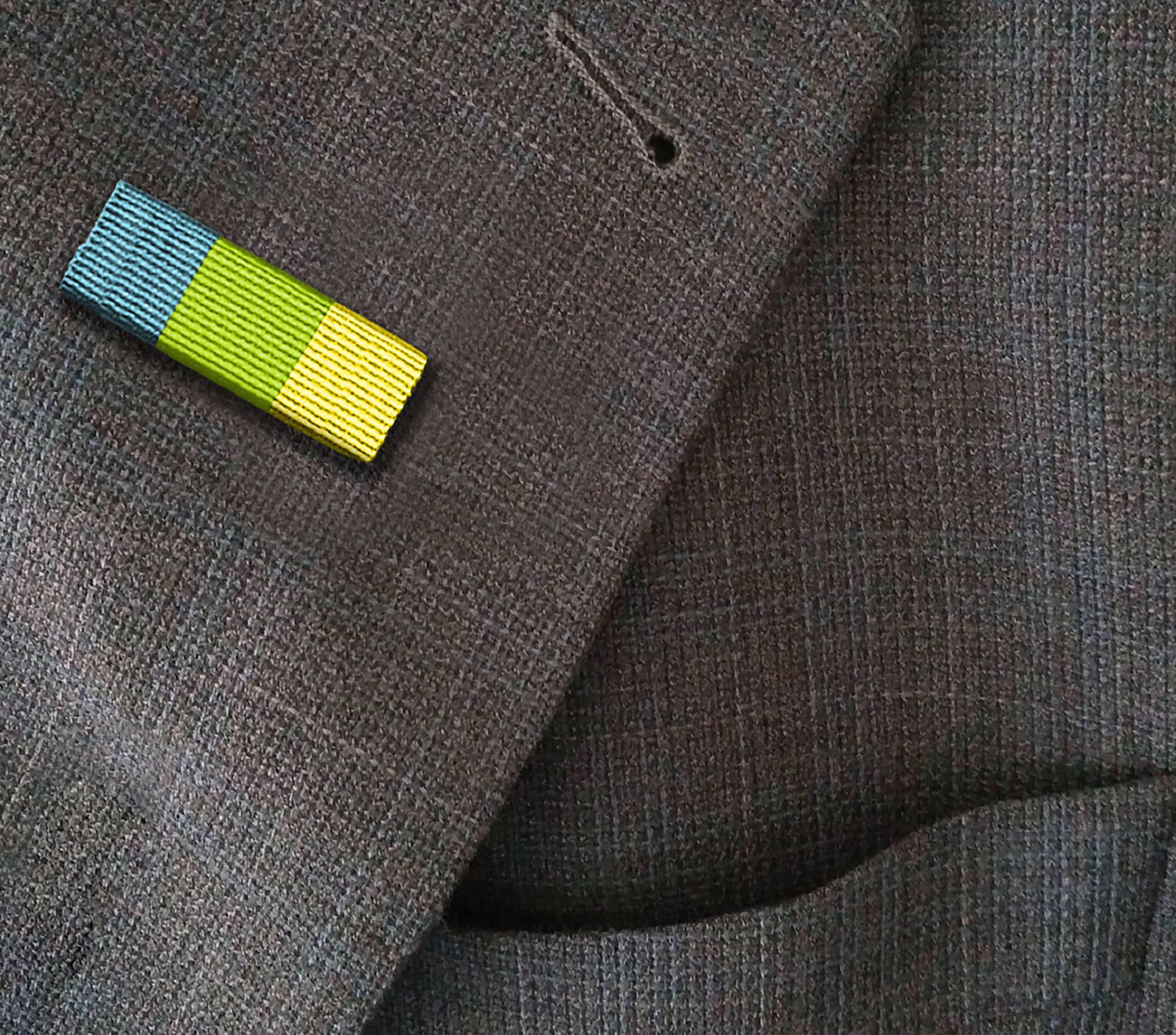 A close-up of a textured brown fabric surface with a small hole near the center. On the lower left, there is a colorful elastic band with blue, yellow, and black stripes.