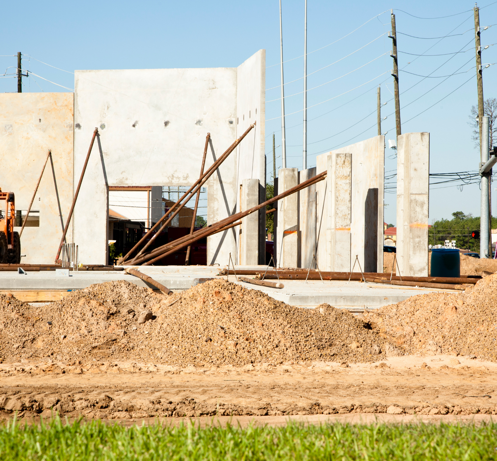 Construction site with partially built walls, construction materials, and dirt foreground.