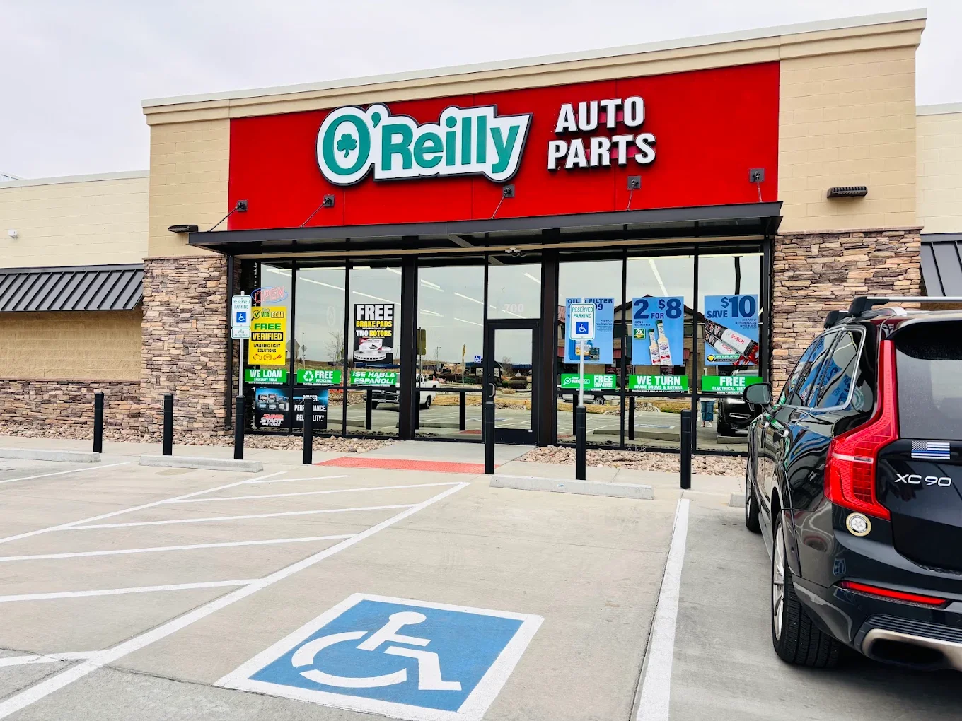 O'Reilly Auto Parts storefront with parking lot, including designated handicapped parking space in foreground, and cars parked outside.