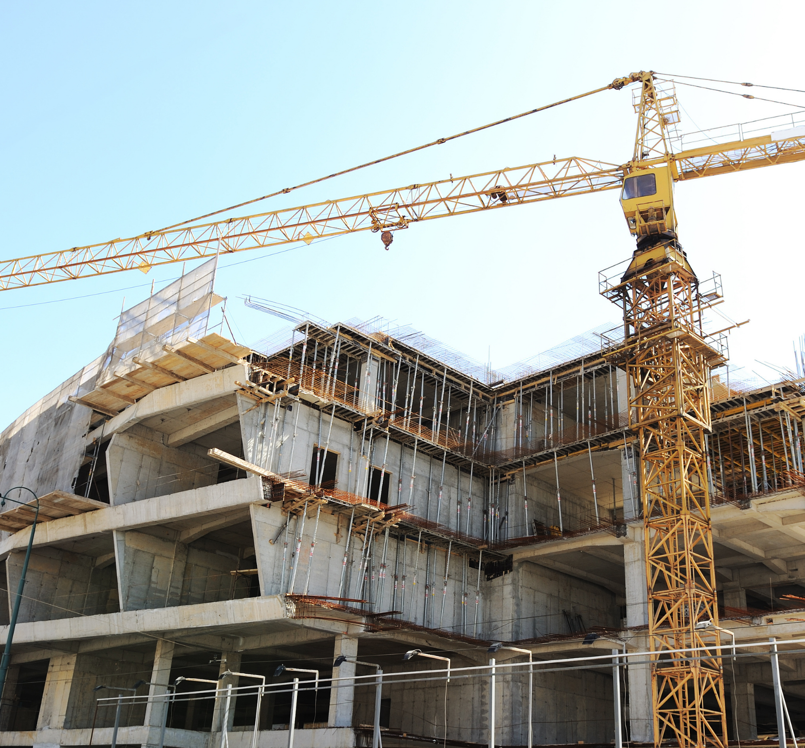 Construction site with a yellow tower crane and building framework.
