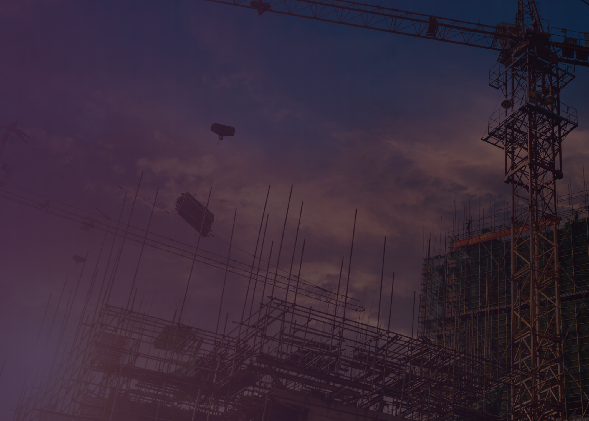 Construction site with scaffolding and a tower crane against the evening sky.