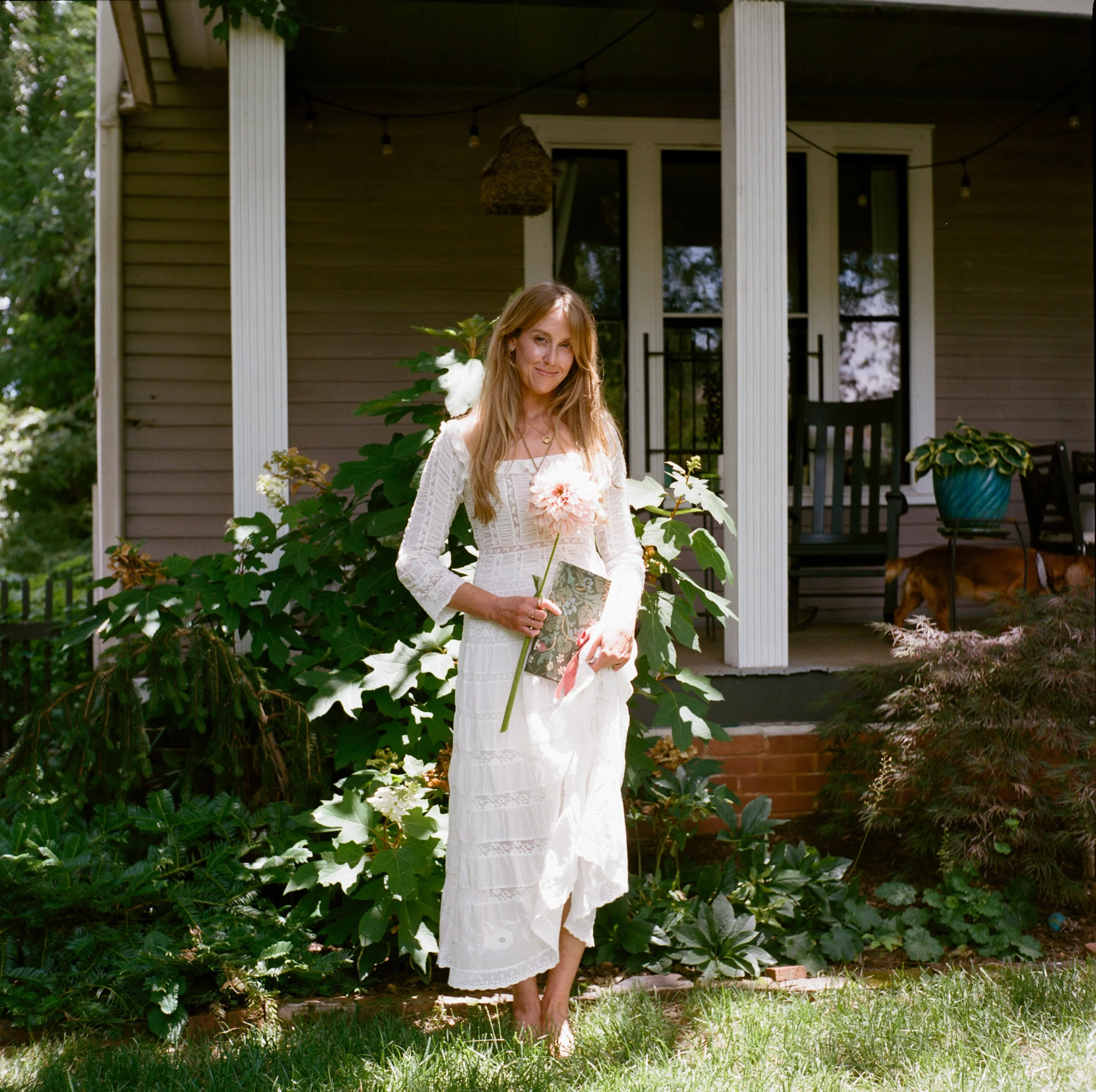 Merci Studio founder and artist Meredith Cochran holding flowers outside her studio.