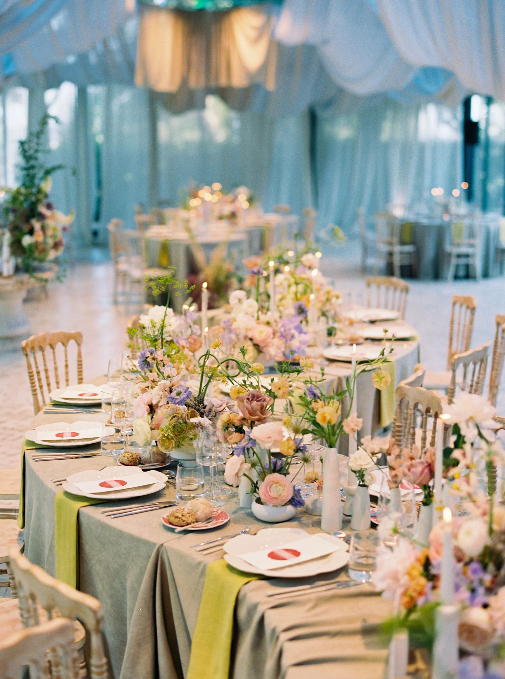 Wedding reception table with custom stationery, florals, candles, and layered place settings.