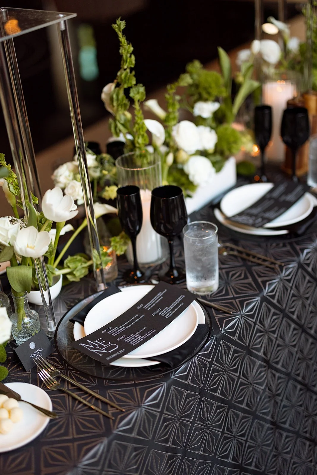 Black and white wedding reception setting with custom paper details, florals, and candlelight.
