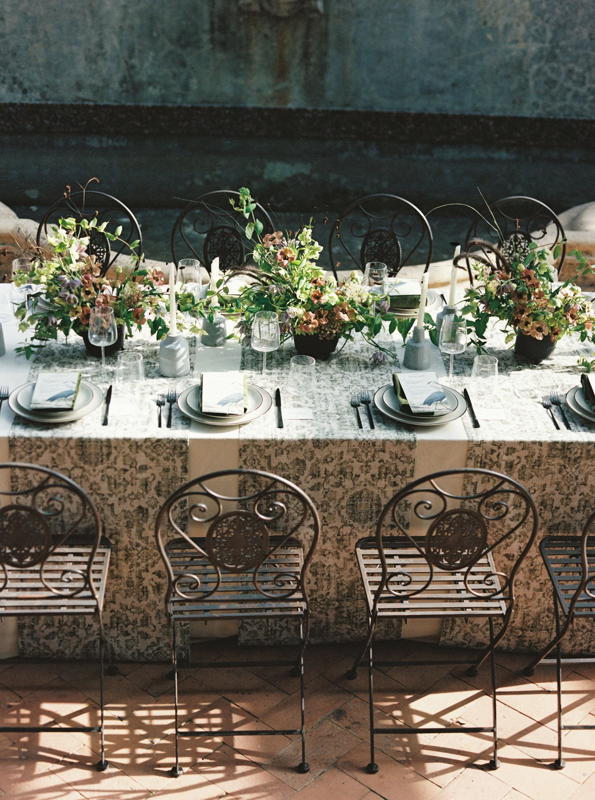 Outdoor wedding dinner with a long banquet table, florals, candles, and custom reception details.