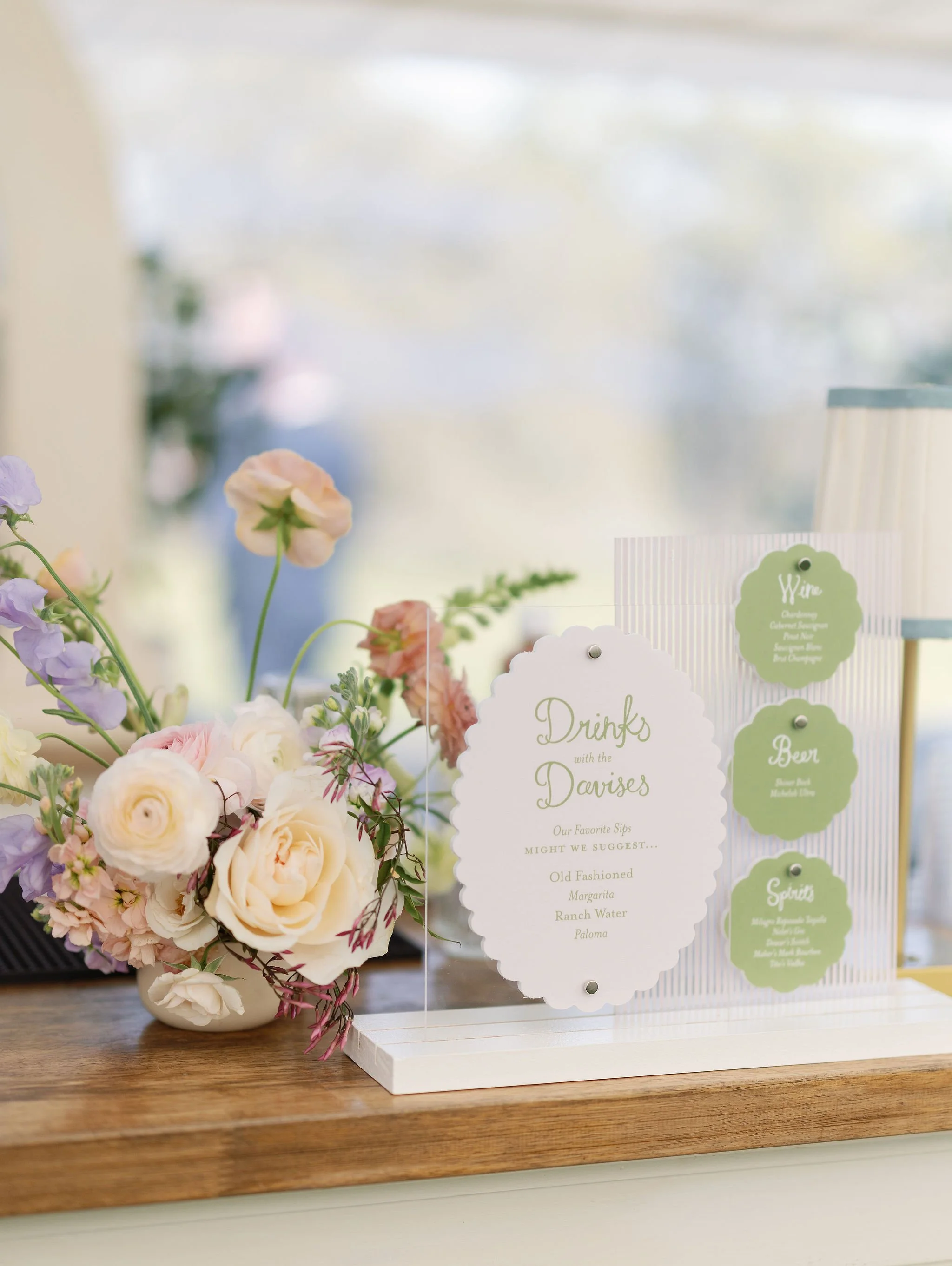 Custom wedding bar signage designed by Merci Studio alongside colorful floral details.