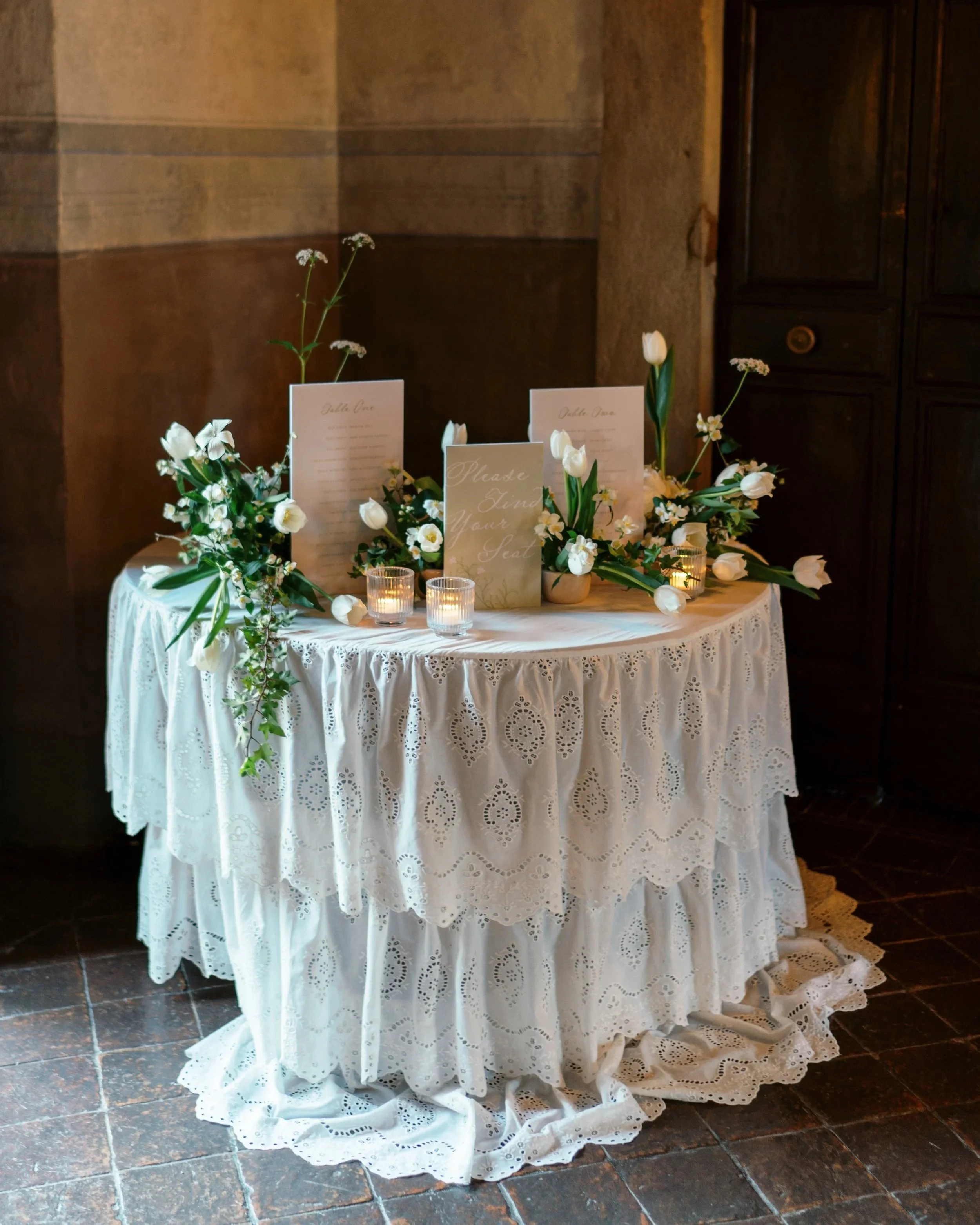 Custom wedding seating display surrounded by white florals and candlelight.