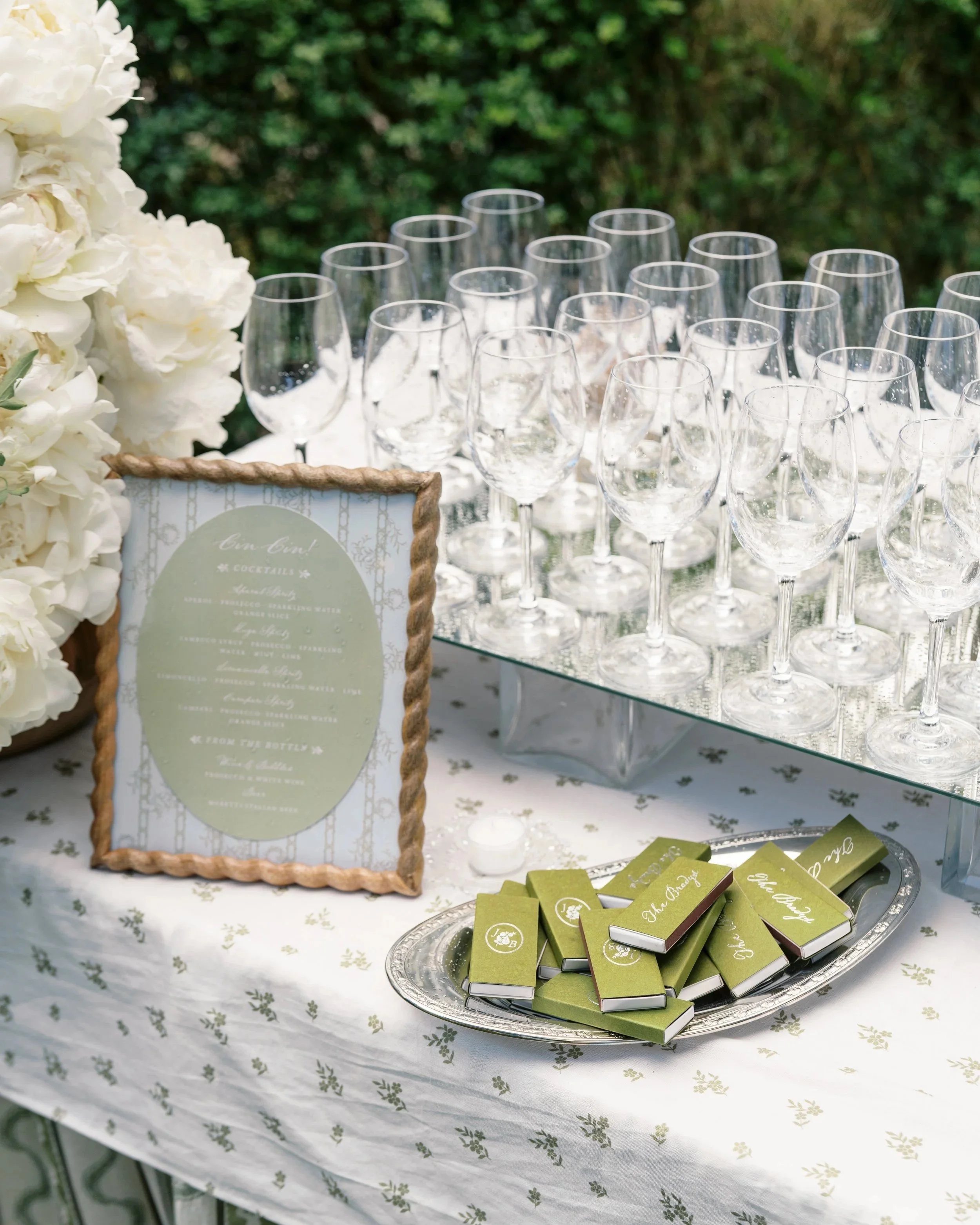 Custom wedding favor boxes and signage displayed with champagne and white florals.