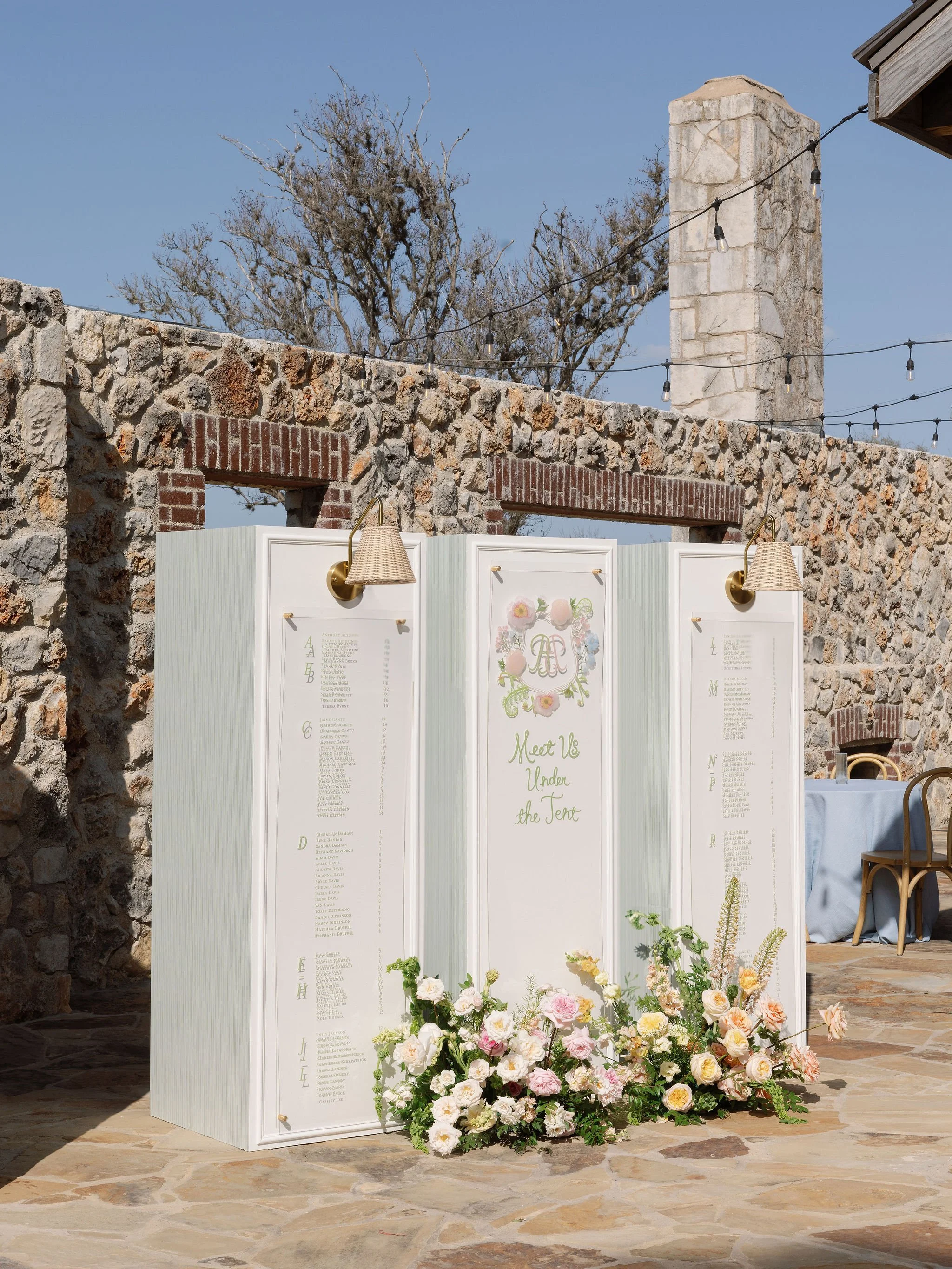 Custom monogrammed wedding seating chart designed by Merci Studio for an outdoor celebration.