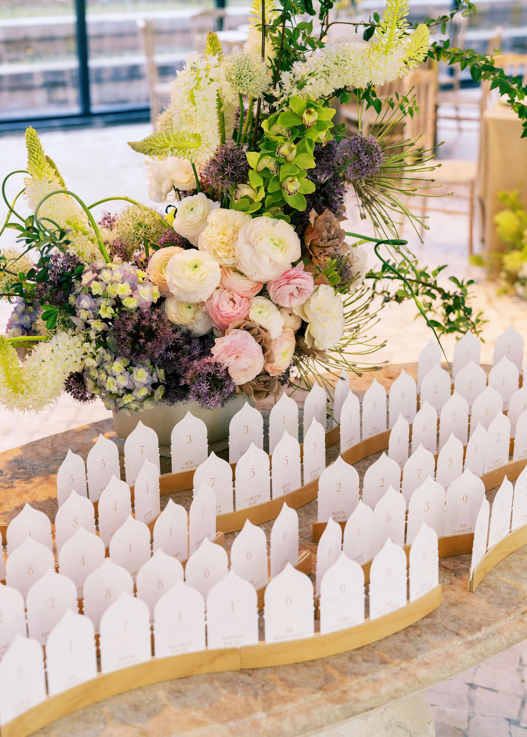 Custom wedding escort cards displayed among colorful florals as part of the reception branding.