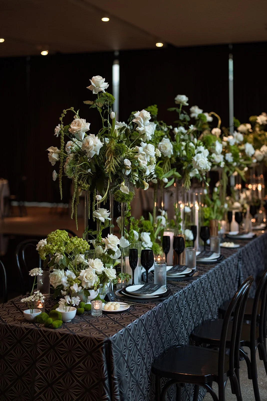 Kristen and Cameron’s wedding reception with white florals, black glassware, candles, and custom event details.