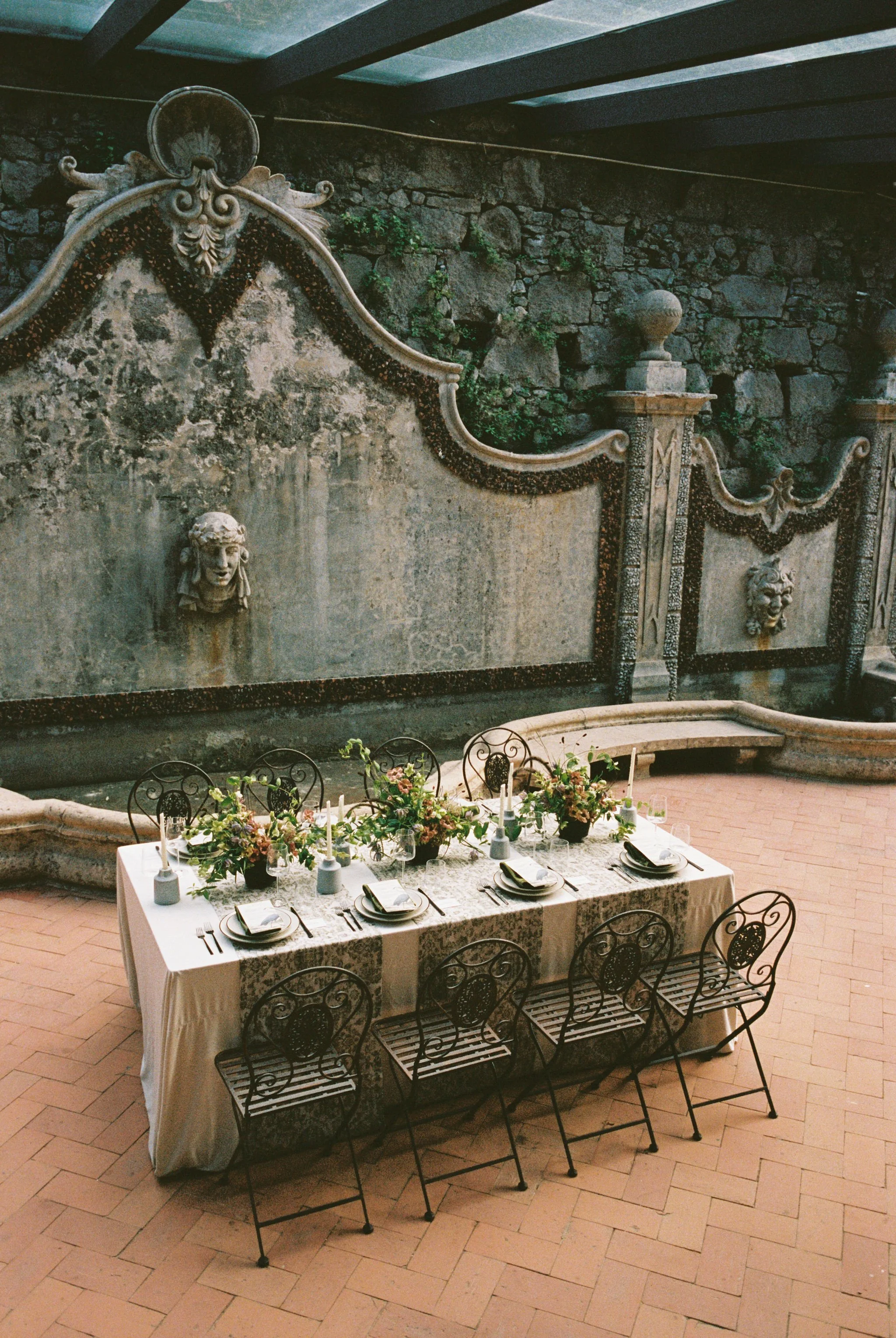 Intimate outdoor wedding reception set within a historic garden courtyard.