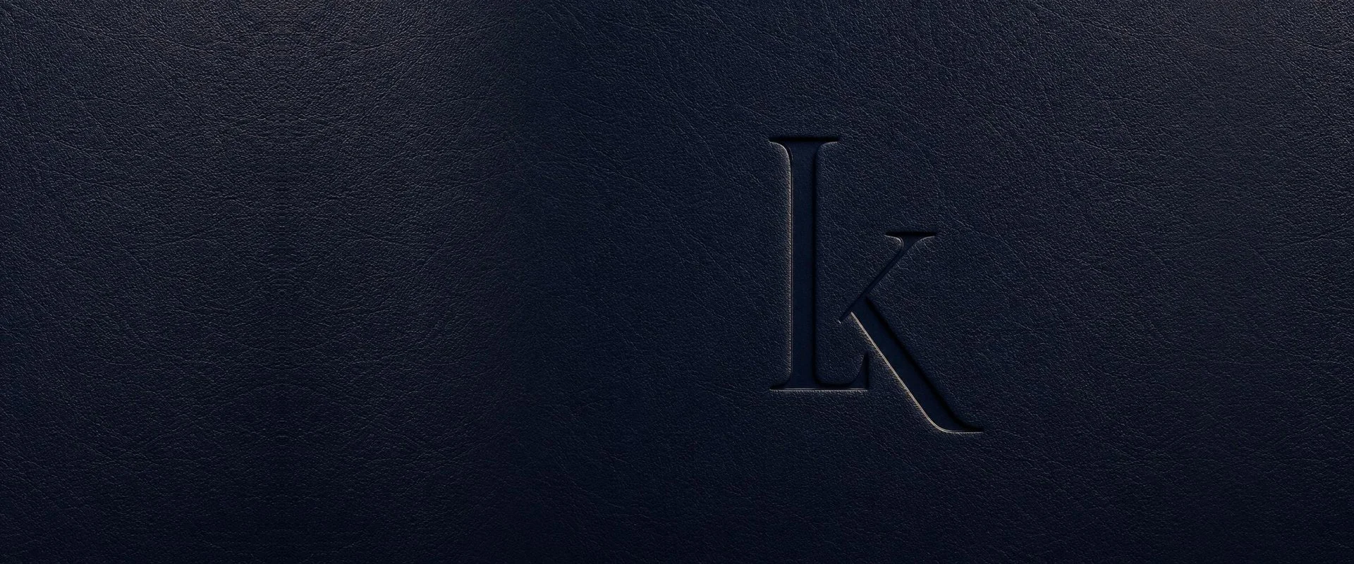 Close-up of a textured dark blue surface with an embossed letter 'K' in the center.