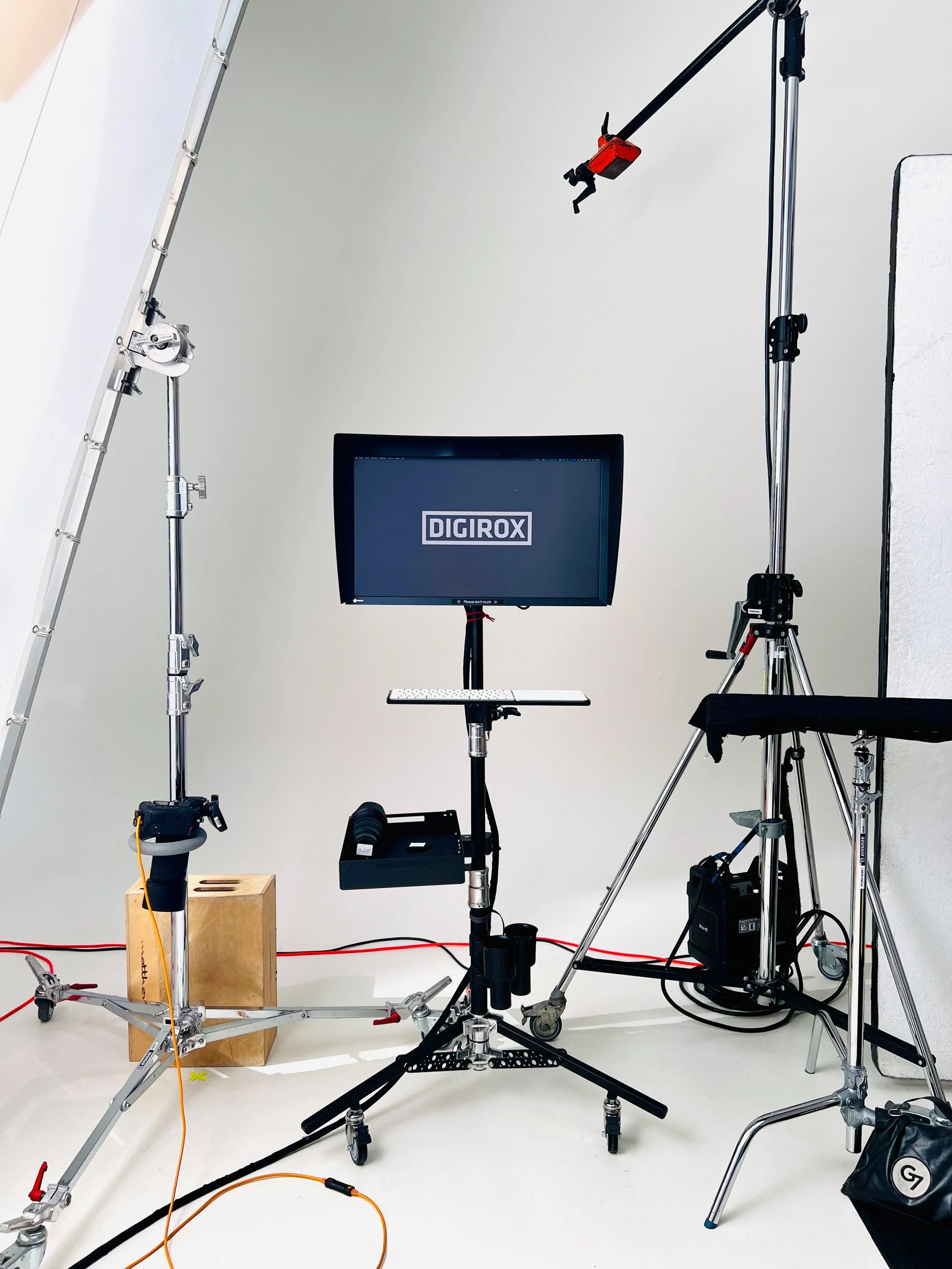 Single monitor on a light stand in a white cyclorama studio, surrounded by Profoto lighting equipment.