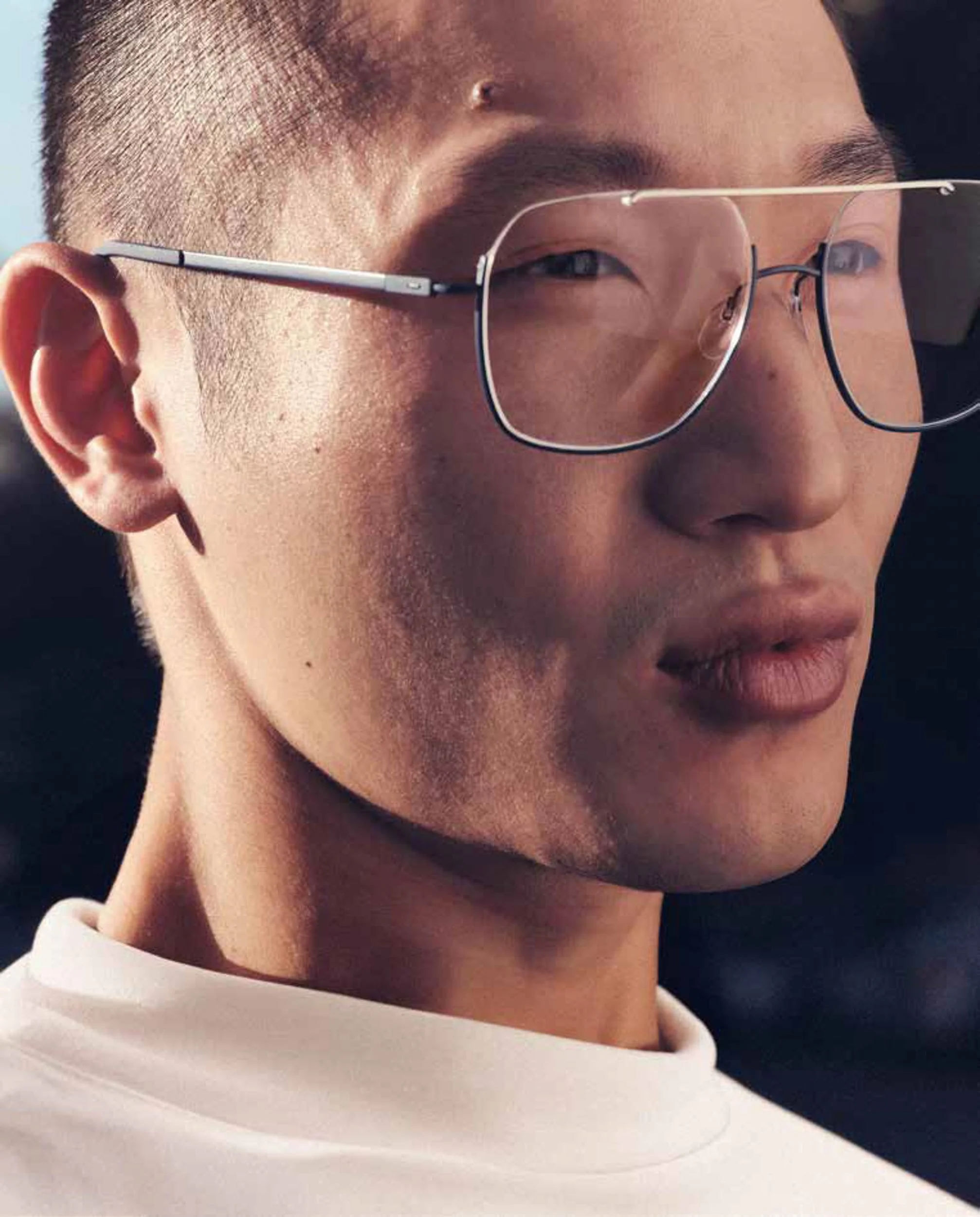 Extreme close-up of a man's face wearing wire-rimmed glasses, with soft directional lighting highlighting his features.