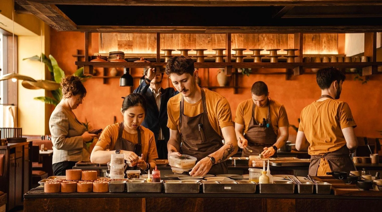People working behind a sushi bar preparing food in a restaurant.