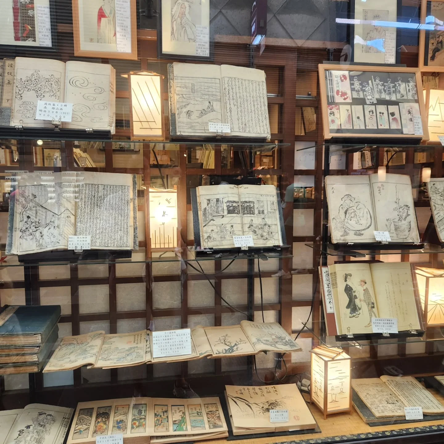Display of traditional Japanese books and illustrated manuscripts in a glass case at a museum or library.