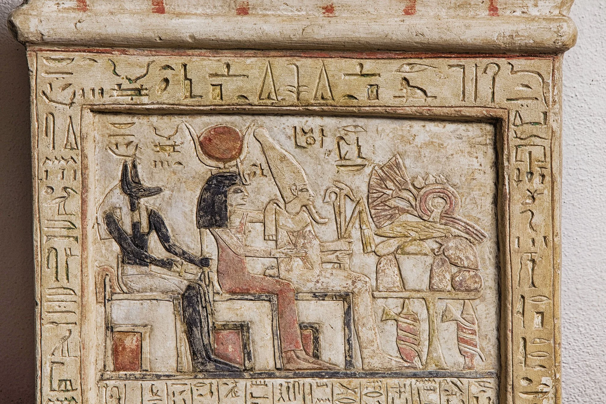 Ancient Egyptian carved stone tablet depicting gods and hieroglyphics.