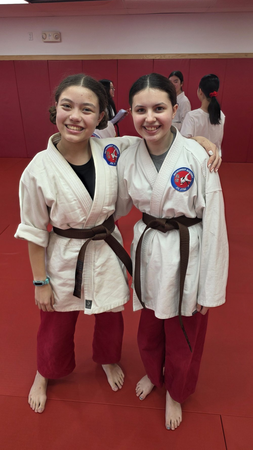 Two Juniors students smiling together in their white gis at the Academy