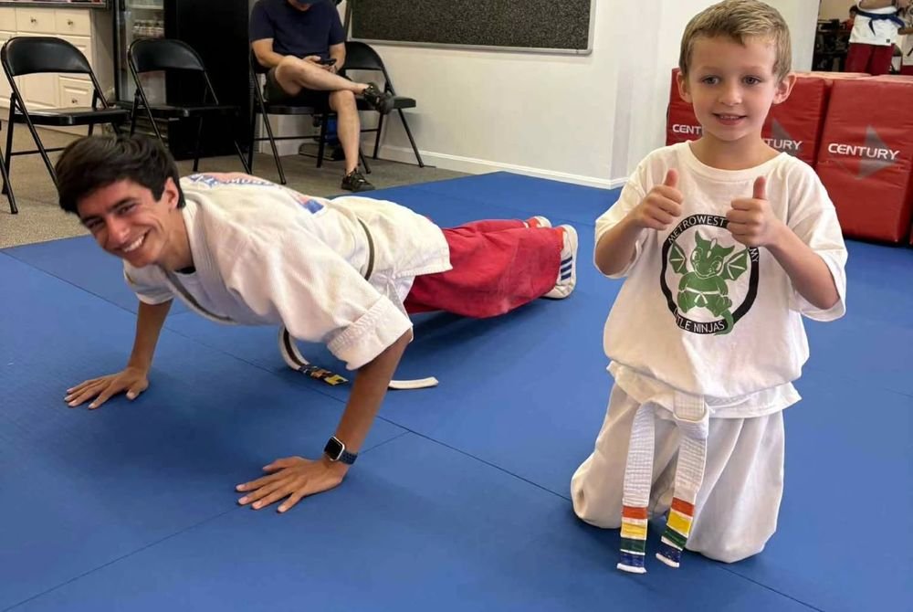 A Ninja Coach doing pushups alongside a Little Ninja giving two thumbs up