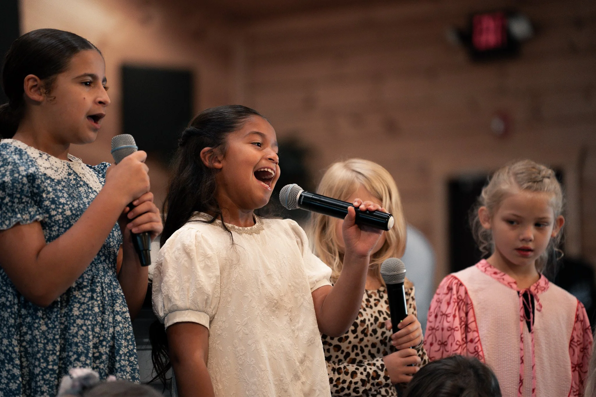 Group of children singing into microphones at a performance or school event