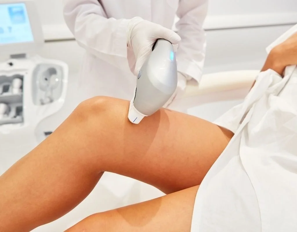 Profissional de saúde realizando procedimento de ultrassom em uma perna de paciente, em ambiente clínico.